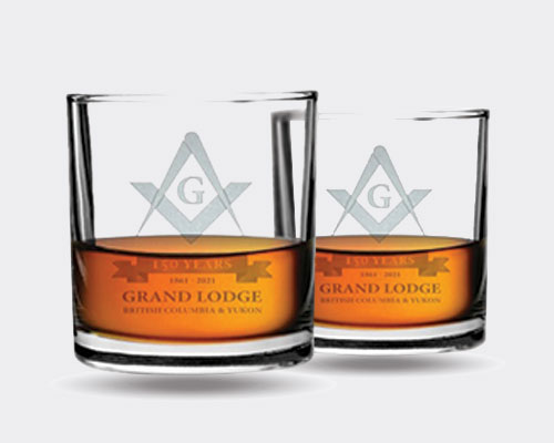 a photograph of two Grand Lodge british columbia and yukon engraved whiskey glass.